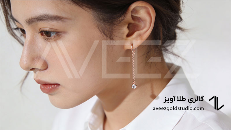 گوشواره آویز ظریف طلای رزگلد با زنجیر باریک و نگین کوچک روی گوش خانم