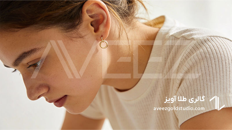 گوشواره ظریف حلقه ای طلای زرد روی گوش یک خانم با استایل ساده و روزمره